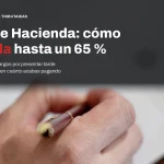 Mano firmando un documento oficial con una pluma sobre una mesa de madera, con el titular sobre cómo reducir una multa de Hacienda